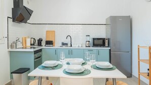 Eine moderne Küche mit türkisfarbenen Schränken, einer weißen Arbeitsplatte und einem Edelstahl-Kühlschrank.