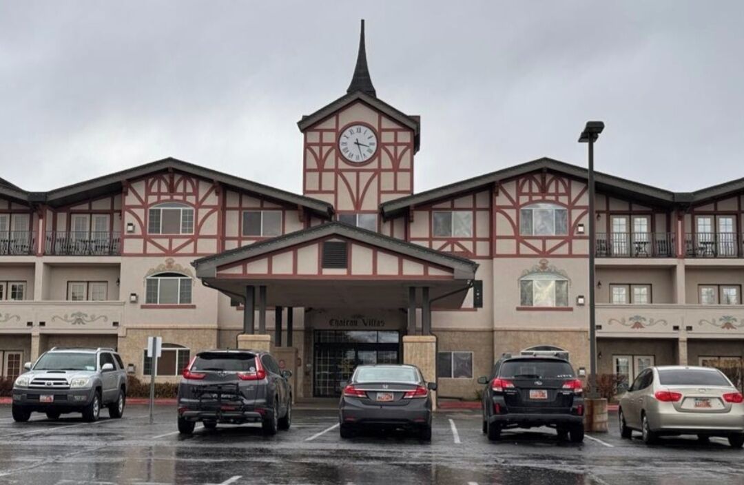 A hotel with a central clock tower, multiple parking spaces, and a traditional architectural style.