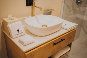 A bathroom with a white sink, a wooden vanity, and a towel with "Jules & Laurent" branding. - Jules and Laurent Hotel Contemporaneo (Ensenada)