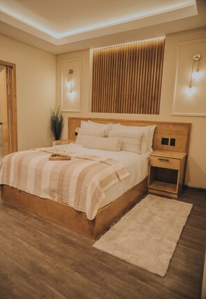 A neatly arranged bedroom with a large bed, bedside tables, a wooden headboard, and a floor lamp. - Jules and Laurent Hotel Contemporaneo (Ensenada)