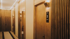 A hotel hallway with wooden doors, a black and white striped carpet, and a sign indicating room number 2. - Jules and Laurent Hotel Contemporaneo (Ensenada)