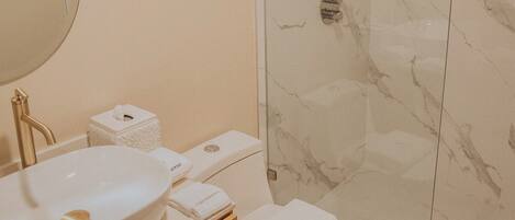 Un bagno moderno con doccia in marmo, lavandino bianco e water.