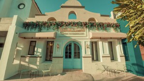 A hotel with a turquoise facade, arched windows, and a sign reading "Jules & Laurent Hotel Contemporaneo." - Jules and Laurent Hotel Contemporaneo (Ensenada)