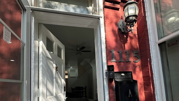Un bâtiment en briques rouges avec une porte blanche et une boîte aux lettres.