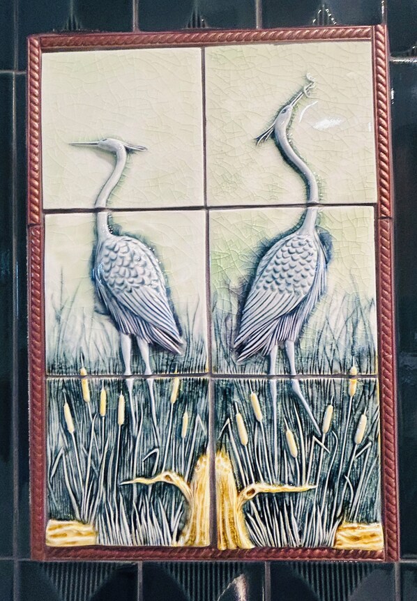 Ein Mosaik von zwei Reihern, die in einem Feld mit hohem Gras stehen.