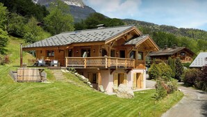 A wooden chalet with a balcony, a stone fireplace, and a view of the mountains. - Chalet Anselme - luxury stay for 10 with Mont Blanc views - OVO Network (Cordon)