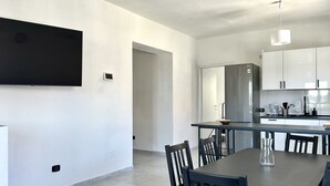A modern kitchen with white cabinets, a stainless steel refrigerator, and a flat-screen TV mounted on the wall. - SE104 - Senigallia, elegant four-room apartment convenient to services (Senigallia)
