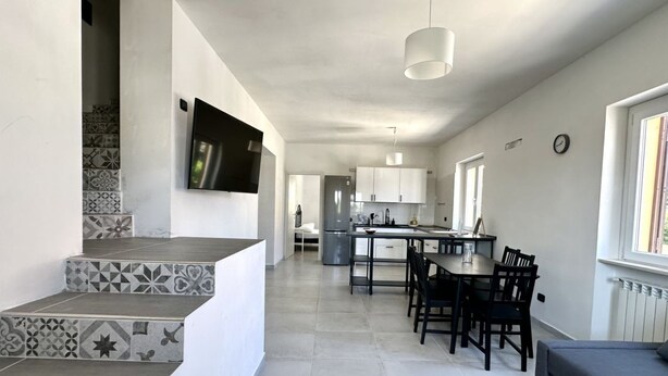 A modern kitchen with white cabinets, a dining table with chairs, and a staircase with patterned tiles. - SE104 - Senigallia, elegant four-room apartment convenient to services (Senigallia)