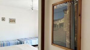 A room with a bed, a ceiling fan, and a framed picture of a building. - RM01 – Senigallia, three-room apartment facing the sea with parking space (Senigallia)