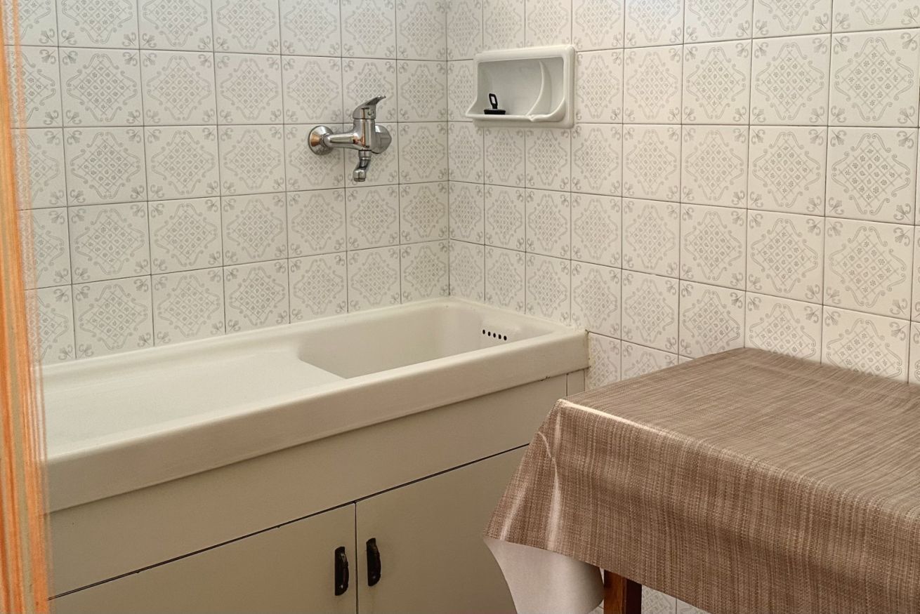 A bathroom with a white sink, a mirror, and a small shelf.