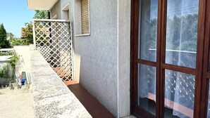 A building with a concrete exterior, a wooden door, and a window with a patterned curtain. - RM01 – Senigallia, three-room apartment facing the sea with parking space (Senigallia)