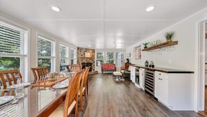 Una cocina amplia con una larga mesa de comedor, sillas de madera y una pared de acento de piedra.