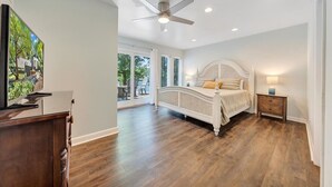 Un dormitorio con una cama grande, ventilador de techo y televisor sobre un mueble de madera.
