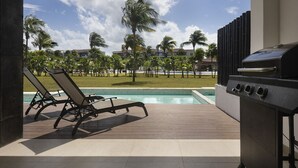 A poolside area with a grill and lounge chairs. - Casa Bonita, Oceanfront, Private pool condo, Mareazul (Playa del Carmen)