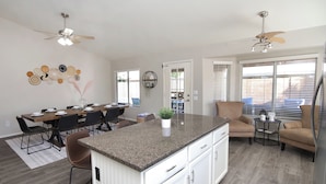 A spacious kitchen with a central island, dining area with chairs, and a seating area with a sofa and chairs.