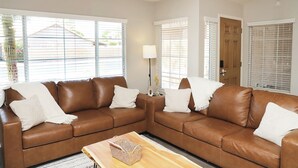 A brown leather sofa with white cushions, a wooden coffee table, and a lamp.