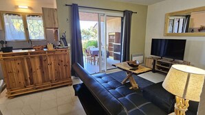 A living room with a sofa, a TV, a lamp, and a wooden dining table.