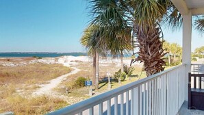 A beach view from a porch with a palm tree, a sign indicating beach access, and a clear sky. - Stunning balcony sunsets, 2 minute walk to beach, lil piece of heaven! (Navarre)