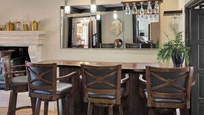 Un'area bar con sgabelli di legno, uno specchio sopra il bancone e una pianta in vaso.