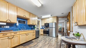 A kitchen with wooden cabinets, a stainless steel refrigerator, and a blue countertop. - Randy's Place - Beautiful 4br W/Private Hot tub! (Bandera)