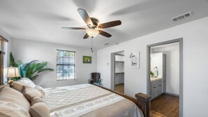 A bedroom with a bed, ceiling fan, window, and a door leading to a bathroom. - Randy's Place - Beautiful 4br W/Private Hot tub! (Bandera)