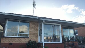 A two-story house with a brick facade, large windows, and a satellite dish.