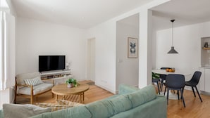 Ein modernes Wohnzimmer mit Flachbildfernseher, rundem Couchtisch und einer Couch.