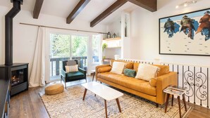 A cozy living room with a fireplace, a sofa, a coffee table, and a large painting on the wall. - Val D Sol Retreat: Perfect Sun Valley Base (Sun Valley)