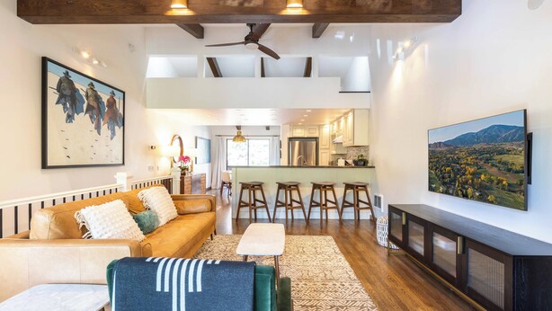 A spacious living area with a high ceiling, a sofa, a coffee table, and a TV mounted on the wall. - Val D Sol Retreat: Perfect Sun Valley Base (Sun Valley)