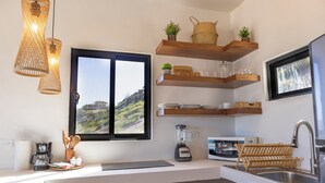 Een moderne keuken met een groot raam, houten planken, een inbouwspoelbak en diverse keukenapparaten.