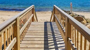 A wooden boardwalk leading to a beach with a clear view of the ocean. - Beachfront Escape in Dennis Port (Dennis Port)