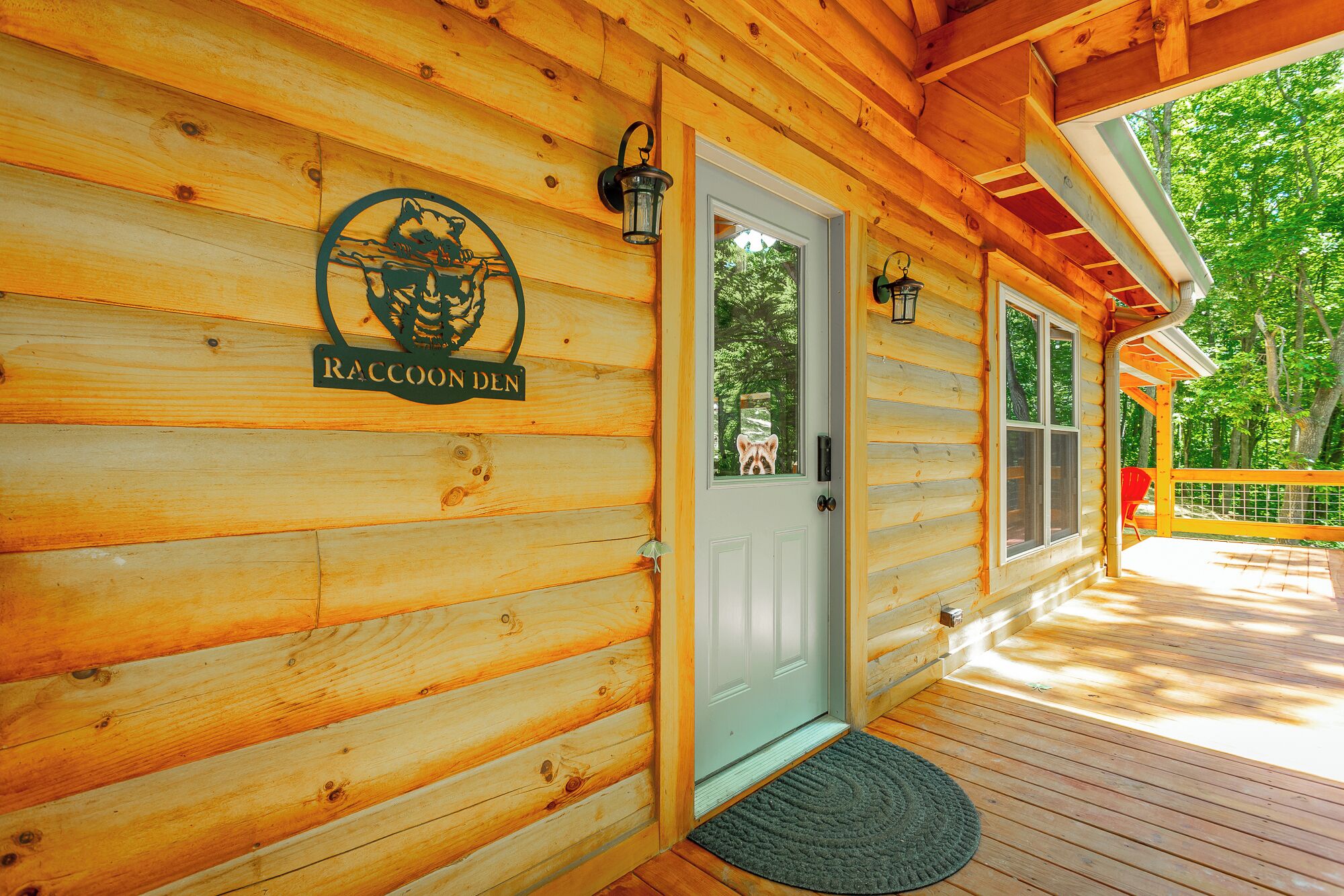 A wooden cabin with a raccoon-themed sign, a door, and a deck.
