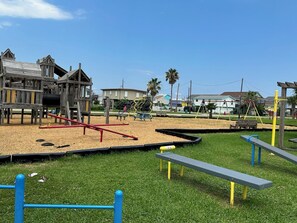 Children can play on the climbing frame, seesaw, and swing set in this outdoor playground.