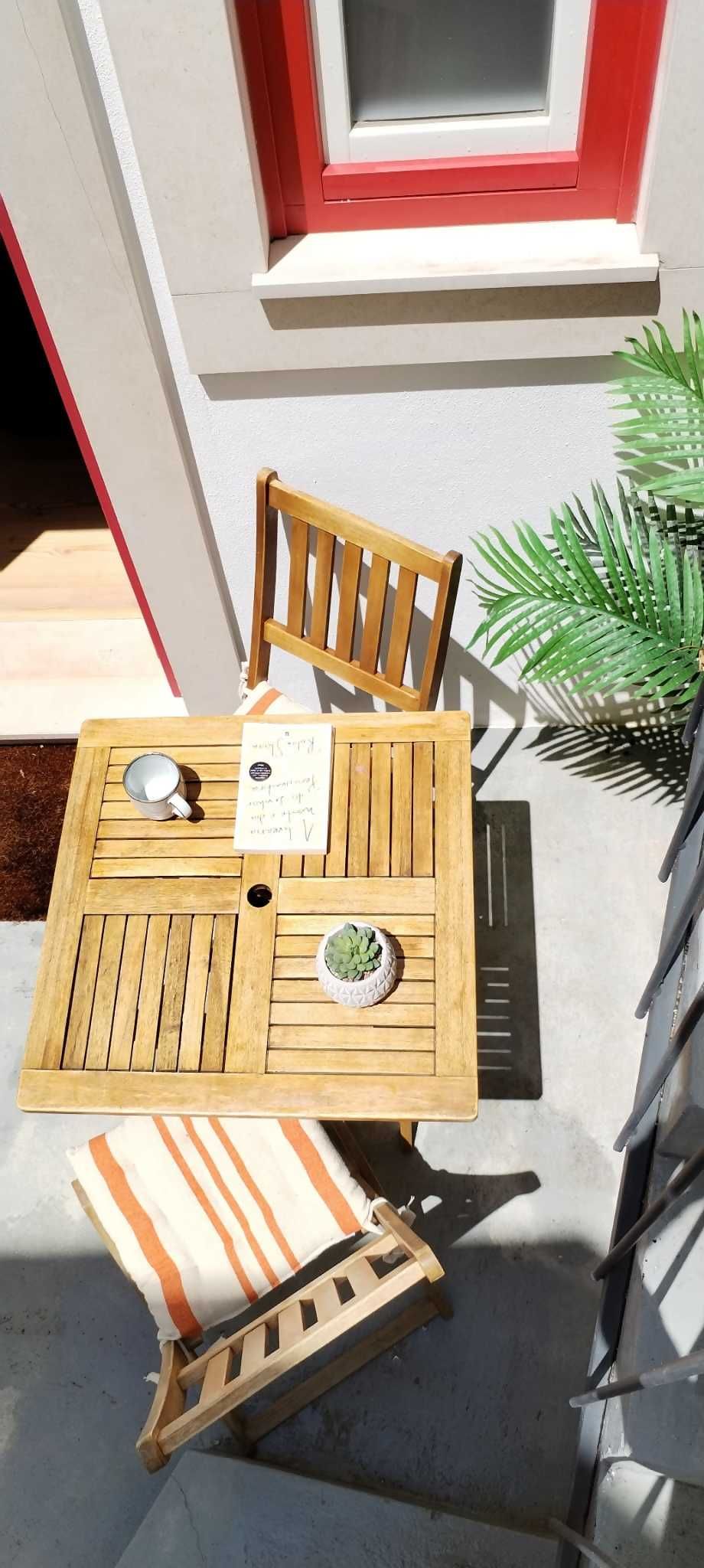 Een houten tafel met twee stoelen en een kleine plant in een pot.