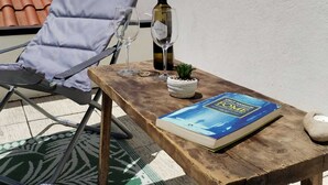Une table en bois sur laquelle se trouvent un livre, une bouteille de vin et un verre.