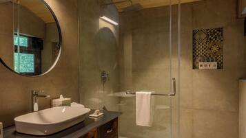 A modern bathroom with a glass-enclosed shower, a round mirror, and wooden cabinetry.