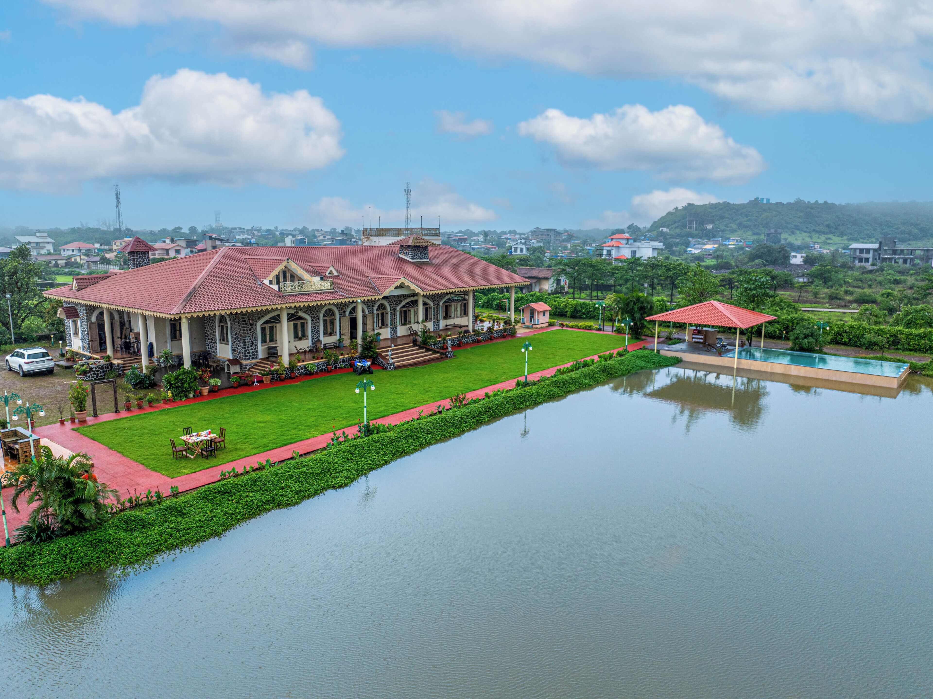 A large building with a red roof, a swimming pool, and a well-maintained lawn.