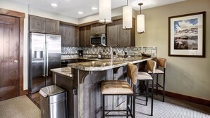 A modern kitchen with a central island, stainless steel appliances, and pendant lighting.