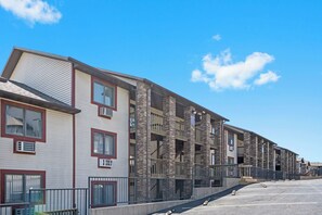 A row of multi-story residential buildings with balconies, air conditioning units, and a clear sky.