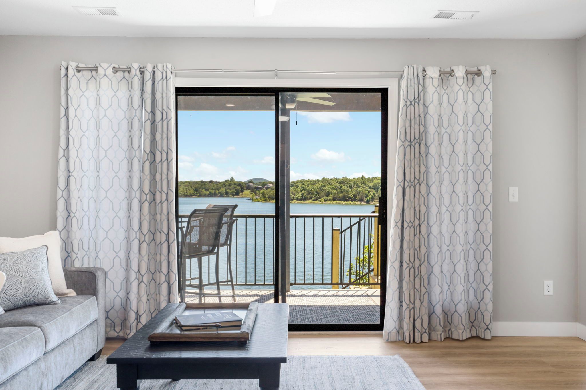 Un salon avec un canapé, une table basse et une vue sur un lac, visible à travers une porte-fenêtre coulissante.