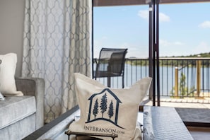 A beige pillow with a house and trees logo on a balcony railing.
