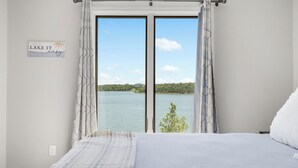 Um quarto com uma cama grande, vista para um lago e um letreiro na parede.