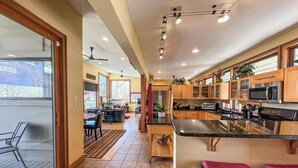 Tilava keittiö, jossa on puiset kaapit, ruostumattomasta teräksestä valmistettu jääkaappi ja suuri keittiösaareke, jonka ympärillä on baarituoleja.