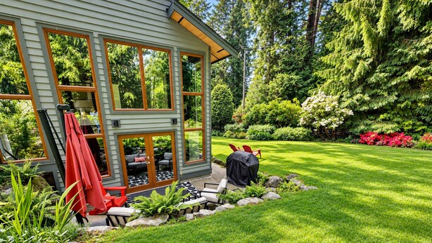 A house with a patio area, outdoor furniture, and a well-maintained garden.
