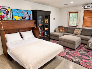 A bedroom with a bed, a sofa, a cabinet, and two wall art pieces. - 2 bedroom Guest Suite with Pool & Sauna access (West Vancouver)