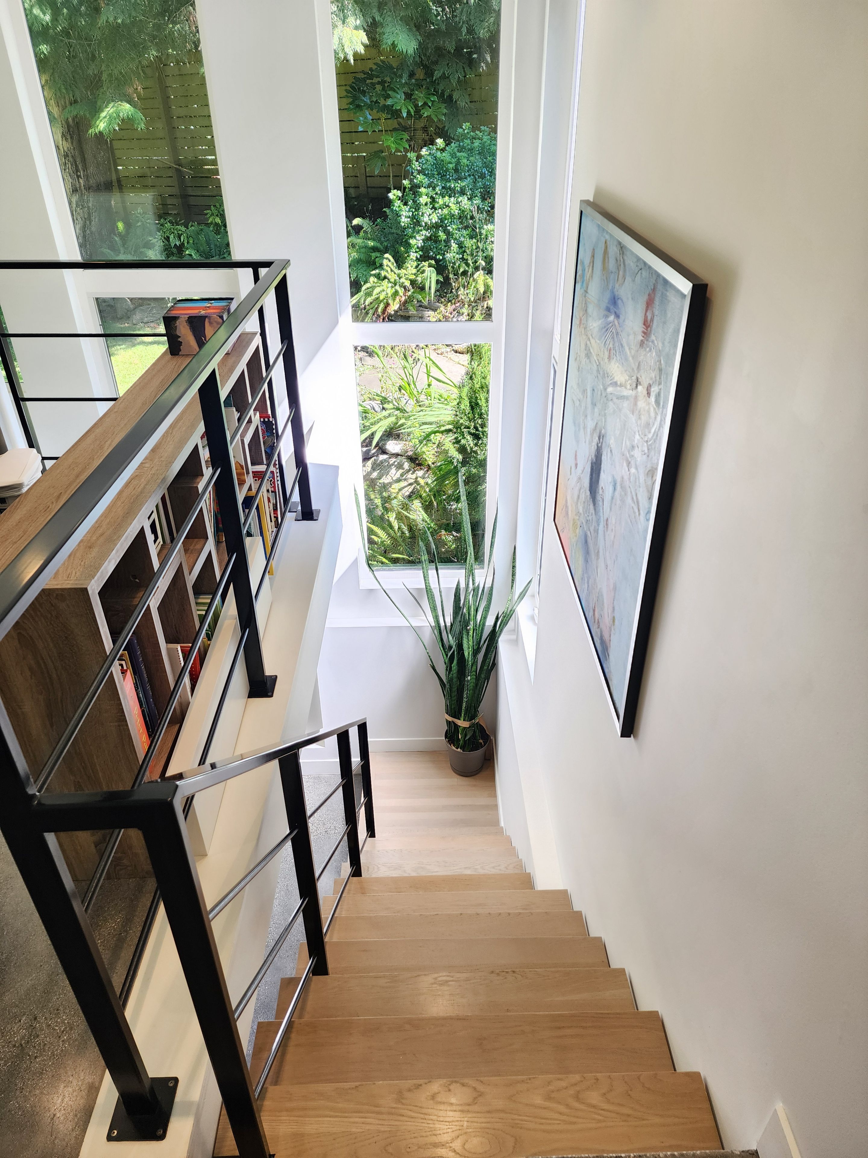 A staircase with a glass railing leading to a balcony with a view of a garden.