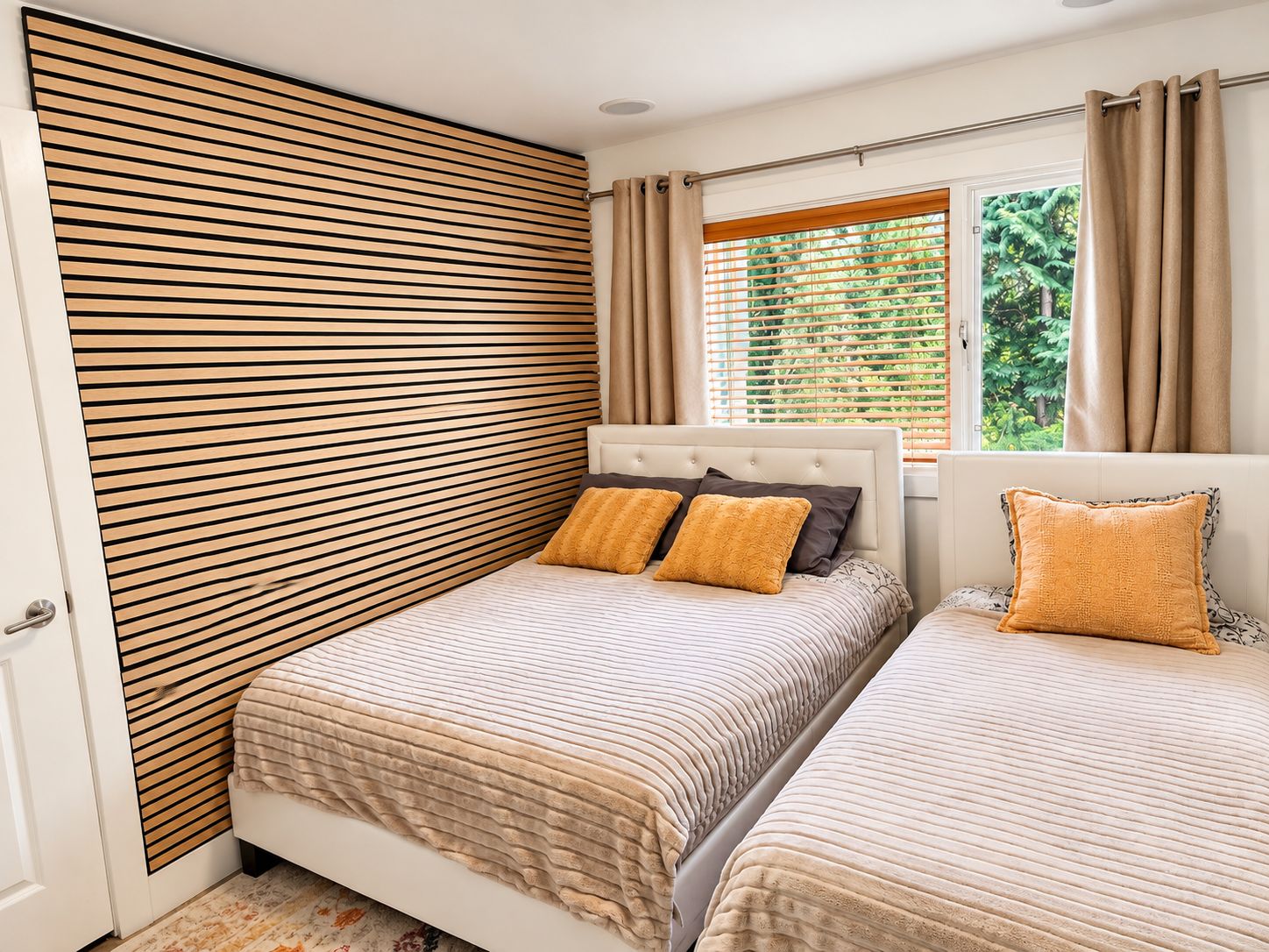 Une chambre avec deux lits, un mur lambrissé en bois, une fenêtre avec des rideaux et une vue sur la verdure.