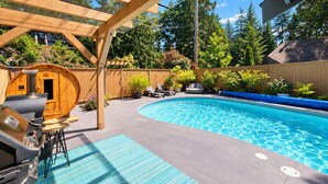 A backyard with a swimming pool, a sauna, and a barbecue area.
