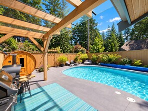 Un jardin avec une piscine, un sauna et un espace barbecue.