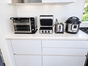 A kitchen counter with a toaster, a waffle maker, a toaster, and a slow cooker. - 2 bedroom Guest Suite with Pool & Sauna access (West Vancouver)